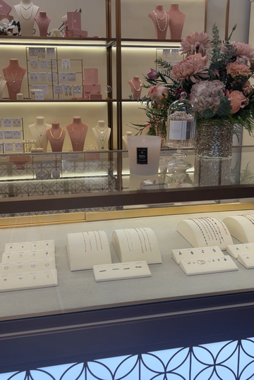Display case with jewelry and flowers in a Natalie Wood Designs store setting
