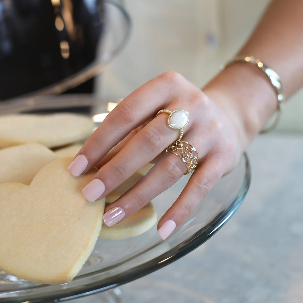 Heart-shaped cookies on a glass plate with a hand reaching out