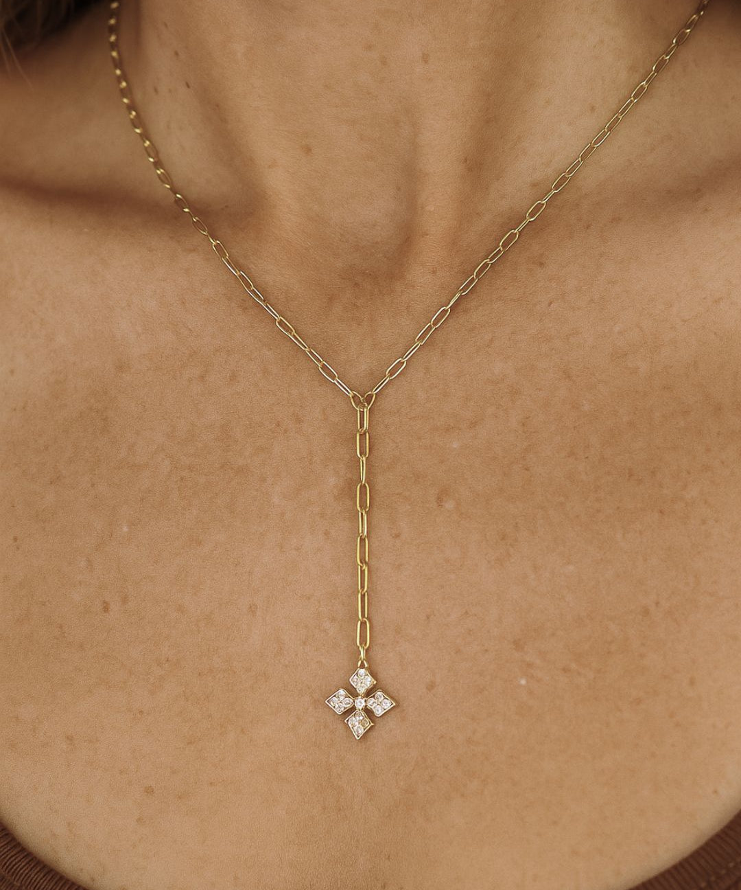 Gold chain necklace with a diamond cross pendant on a person's neck