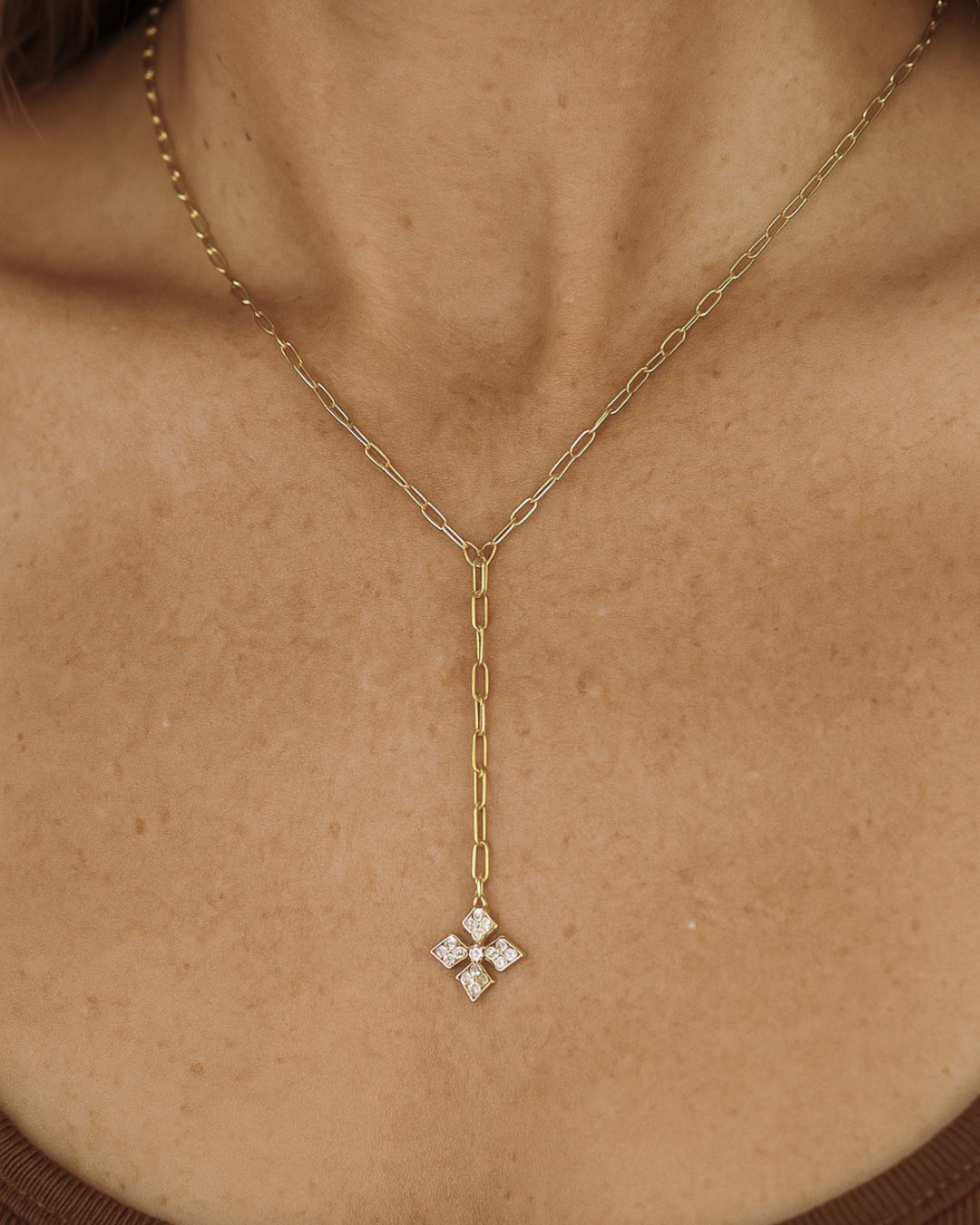 Gold chain necklace with a diamond cross pendant on a person's neck