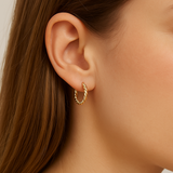 Close-up of a person wearing a gold hoop earring with a neutral background