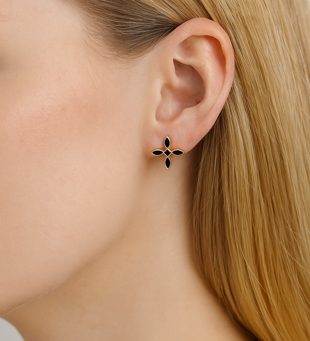 Close-up of a woman with blonde hair wearing a black and gold cross earring.