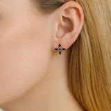 Close-up of a woman with blonde hair wearing a black and gold cross earring.