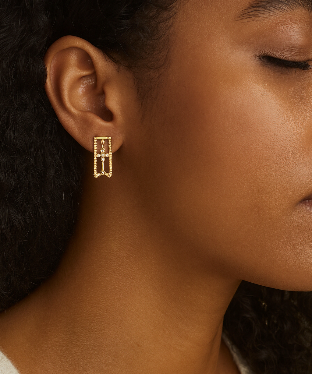 Close-up of a person wearing gold earrings with a blurred background
