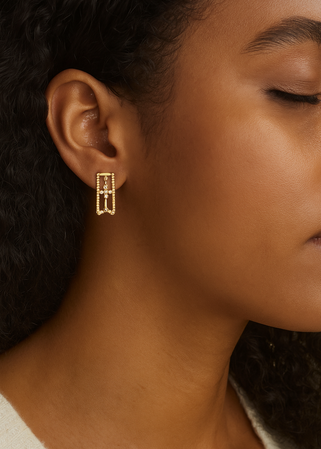 Close-up of a person wearing gold earrings with a blurred background
