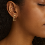 Close-up of a person wearing gold earrings with a blurred background