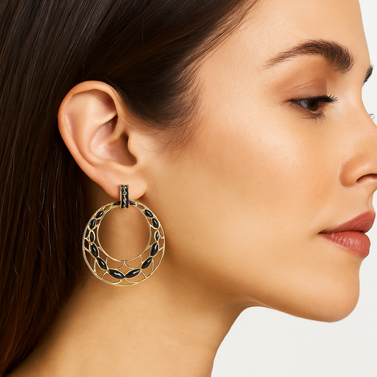 Close-up of a woman wearing gold statement earrings with black Enamel on a neutral background