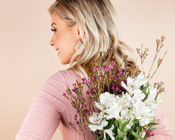 Woman holding a bouquet of flowers against a beige background