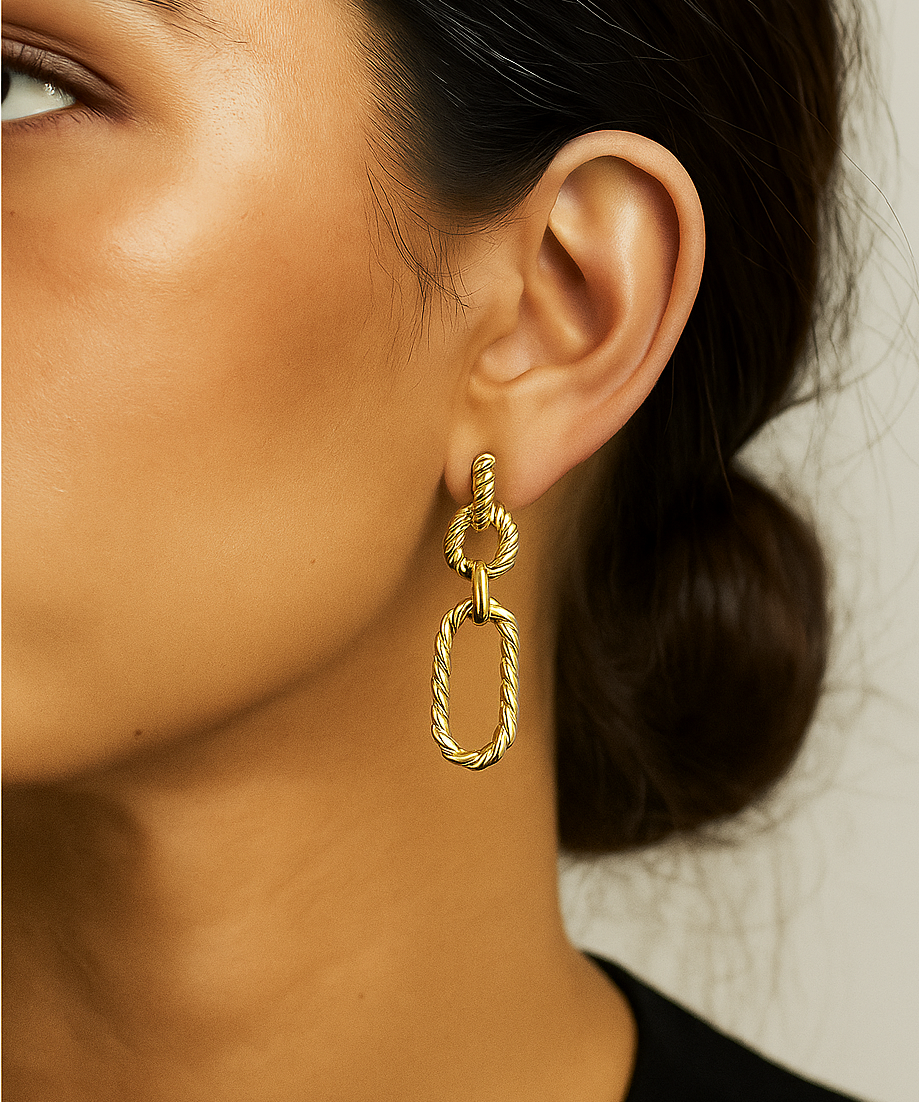 Gold link statement earring worn by a person with a neutral background