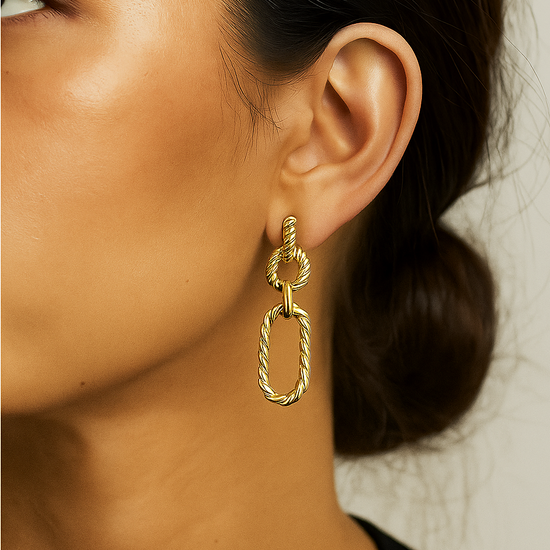 Gold link statement earring worn by a person with a neutral background