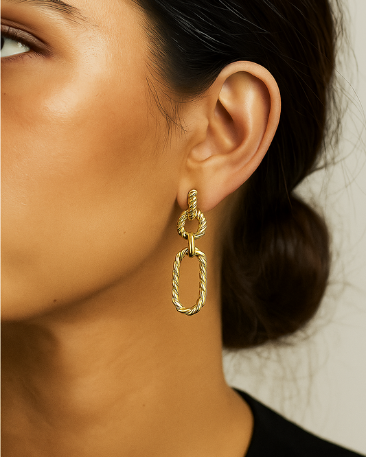 Gold link statement earring worn by a person with a neutral background