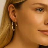 Close-up of a woman wearing gold scallop hoop earring