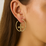 Close-up of a person wearing gold hoop earrings and a gold chain necklace.