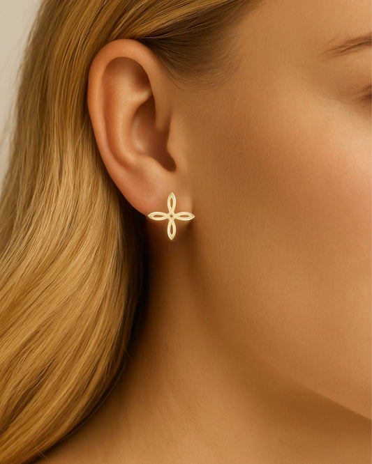 Gold cross earring worn by a person with blonde hair.