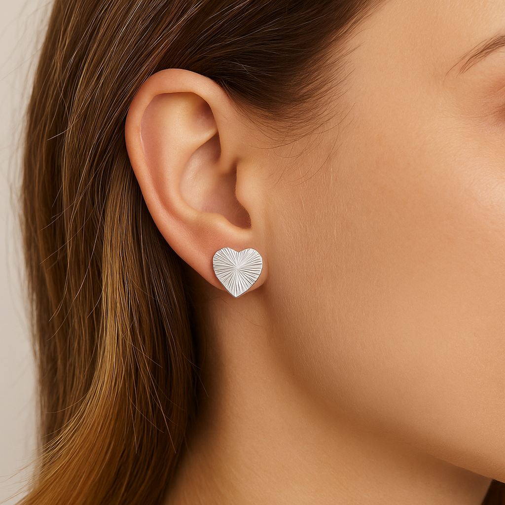 Close-up of a person wearing silver heart-shaped earrings.